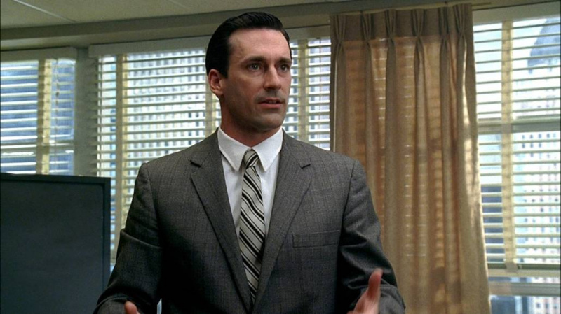 Don Draper em um terno cinza claro, gravata listrada e camisa branca