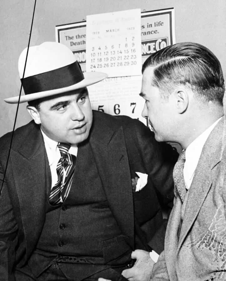 Capone v tmavém třídílném obleku s kontrastním kloboukem
