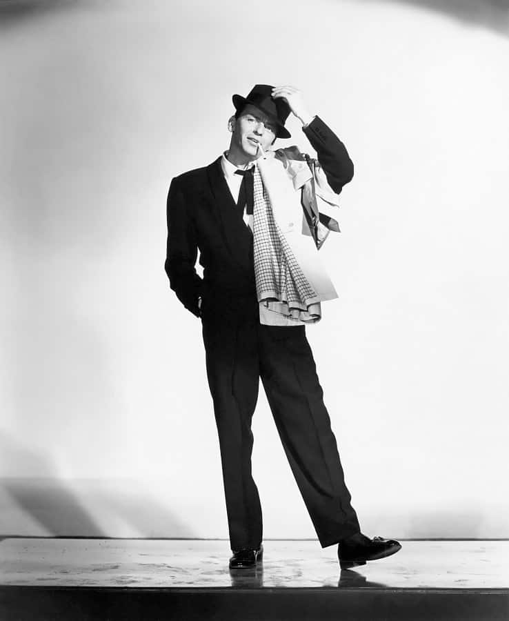 Sinatra em smoking de gola xale com gravata borboleta desamarrada e trench coat