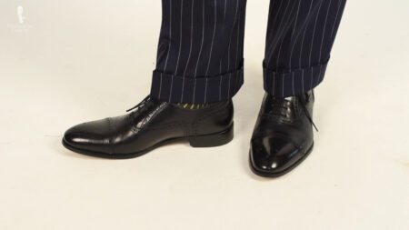Sapatos de couro pretos usados ​​​​com um terno de risca de giz marinho escuro