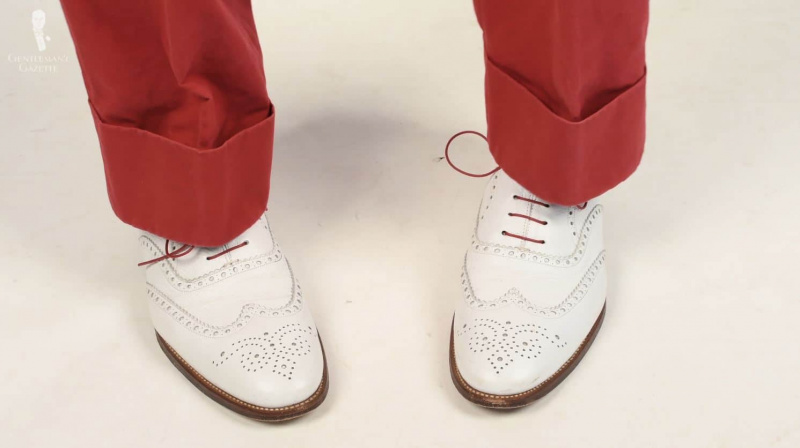 Fanfarrão branco usado com calças vermelhas e cadarços coloridos