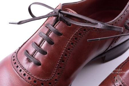 Cadarços marrons escuros usados ​​em um sapato sangue de boi