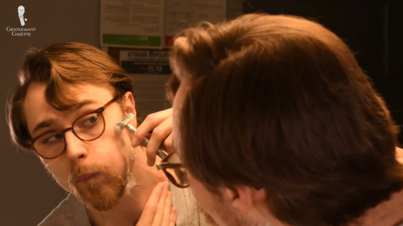 Preston fazendo a barba ao redor de suas bochechas com uma navalha DE