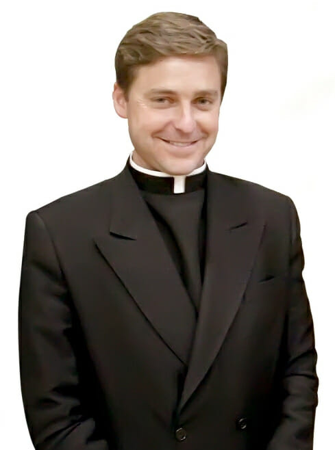 Auteur et commentateur le P. Jonathan Morris portant un rabat (dickie clérical) avec une veste noire à double boutonnage