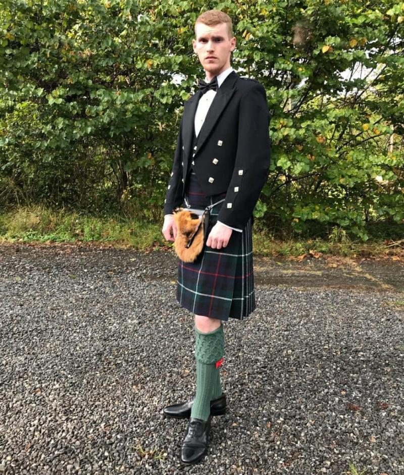 Rapaz jovem em vestido escocês das montanhas
