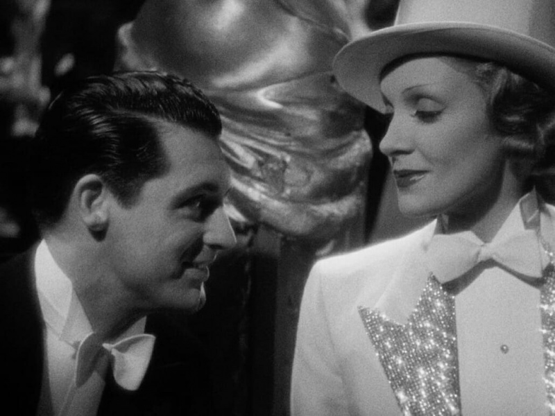   Dietrich v třpytivém fraku s Cary Grantem s motýlkem na jednom konci se souborem bílé kravaty