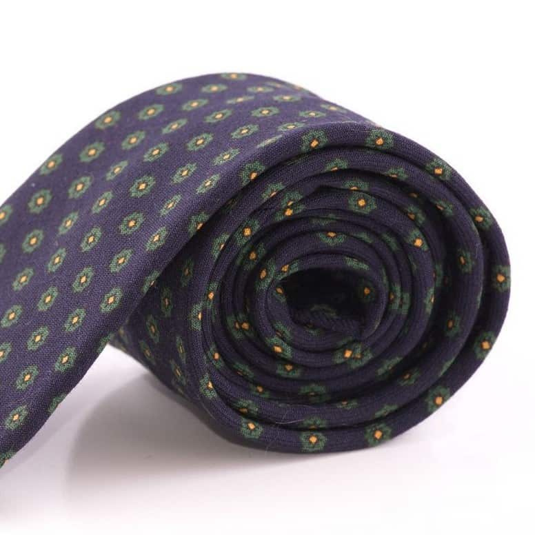 Een foto van een donkerblauwe stropdas met groen geometrisch patroon
