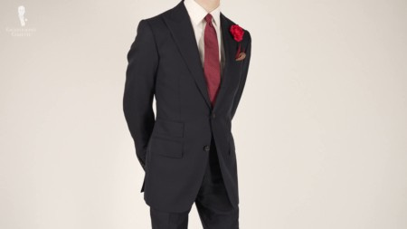 Preston v černém obleku spárovaném s červenou mikrotečkovanou kravatou s červenou růží a potištěným kapesníčkem.