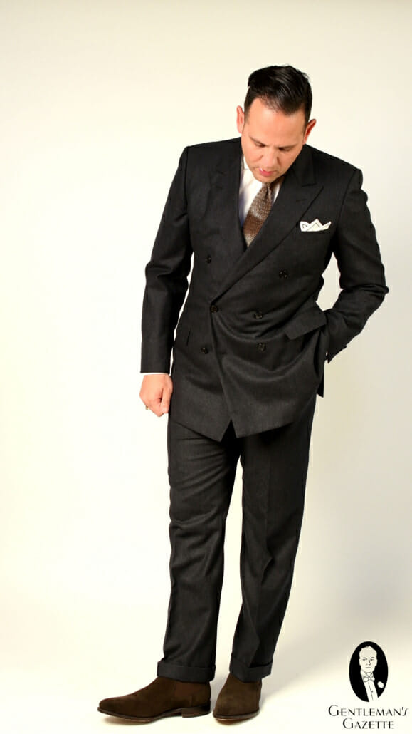 Sven Raphael Schneider usa um terno clássico de flanela cinza com gravata de malha e botas Chelsea de camurça marrom escuro
