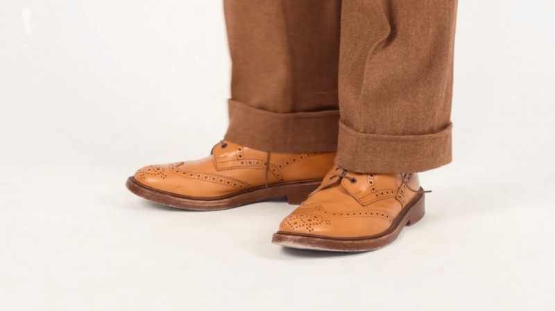 Hnědé boty s dvojitou podrážkou od Trickers, které se nosí s hnědým oblekem s rybí kostí