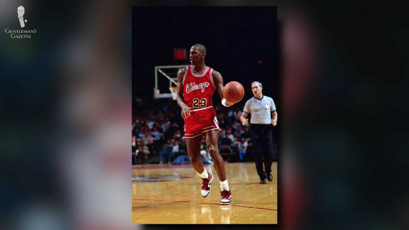 Michael Jordan vestindo um par de Nike Air Jordans vermelho e branco enquanto jogava basquete.