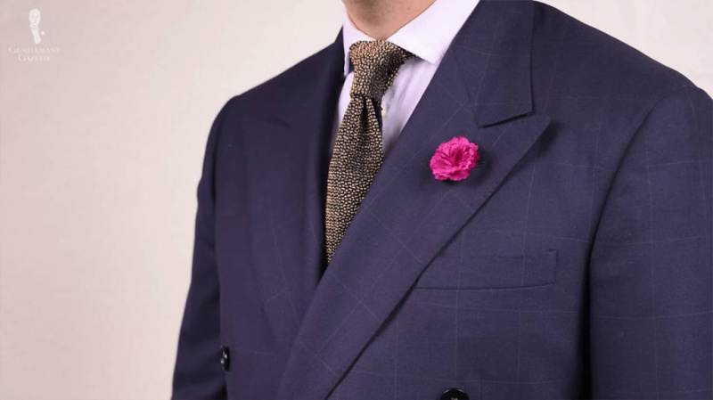 Veste de costume bleu marine accessoirisée avec une cravate en tricot et une boutonnière rose