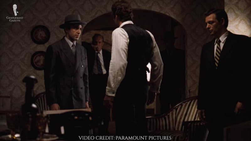 Michael Corleone v šedém dvouřadovém obleku a klobouku Homburg.