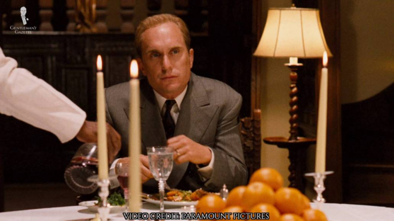 Tom Hagen na večeři ve stejném šedém obleku.